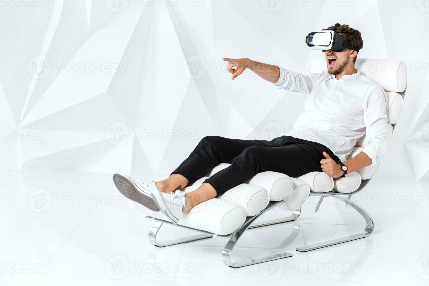 Excited young man is getting experience using VR-headset glasses of virtual reality gesticulating with his hands photo
