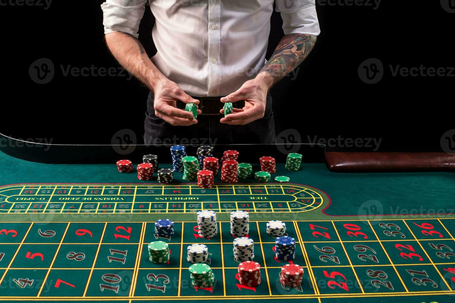 A close-up vibrant image of green casino table with roulette, with the hands of croupier and multicolored chips. photo