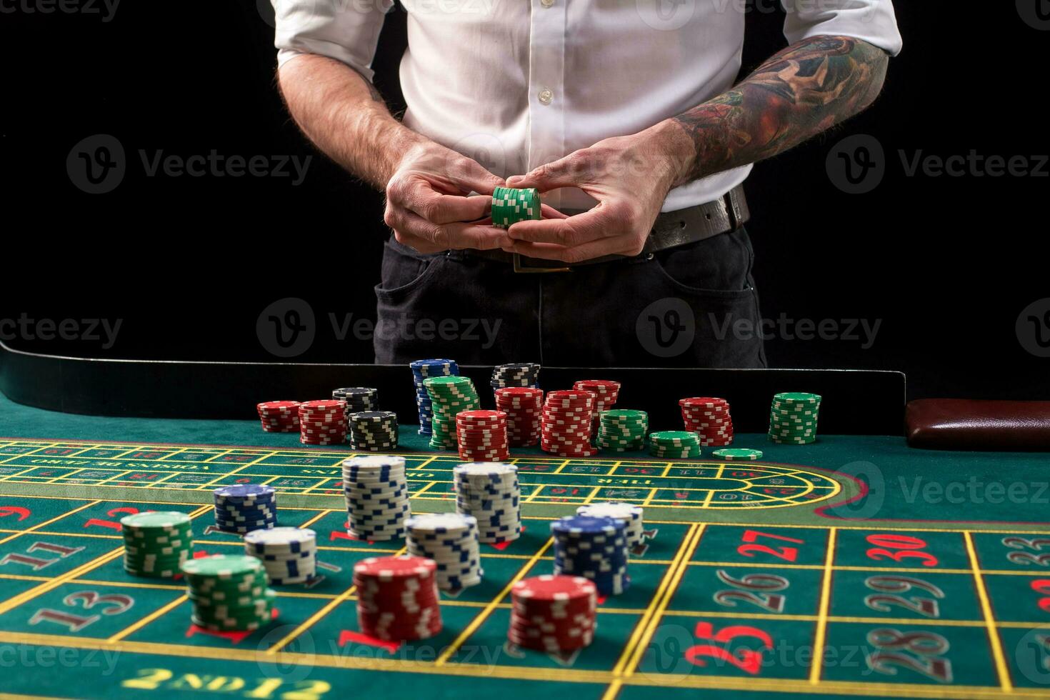 A close-up vibrant image of green casino table with roulette, with the hands of croupier and multicolored chips. photo