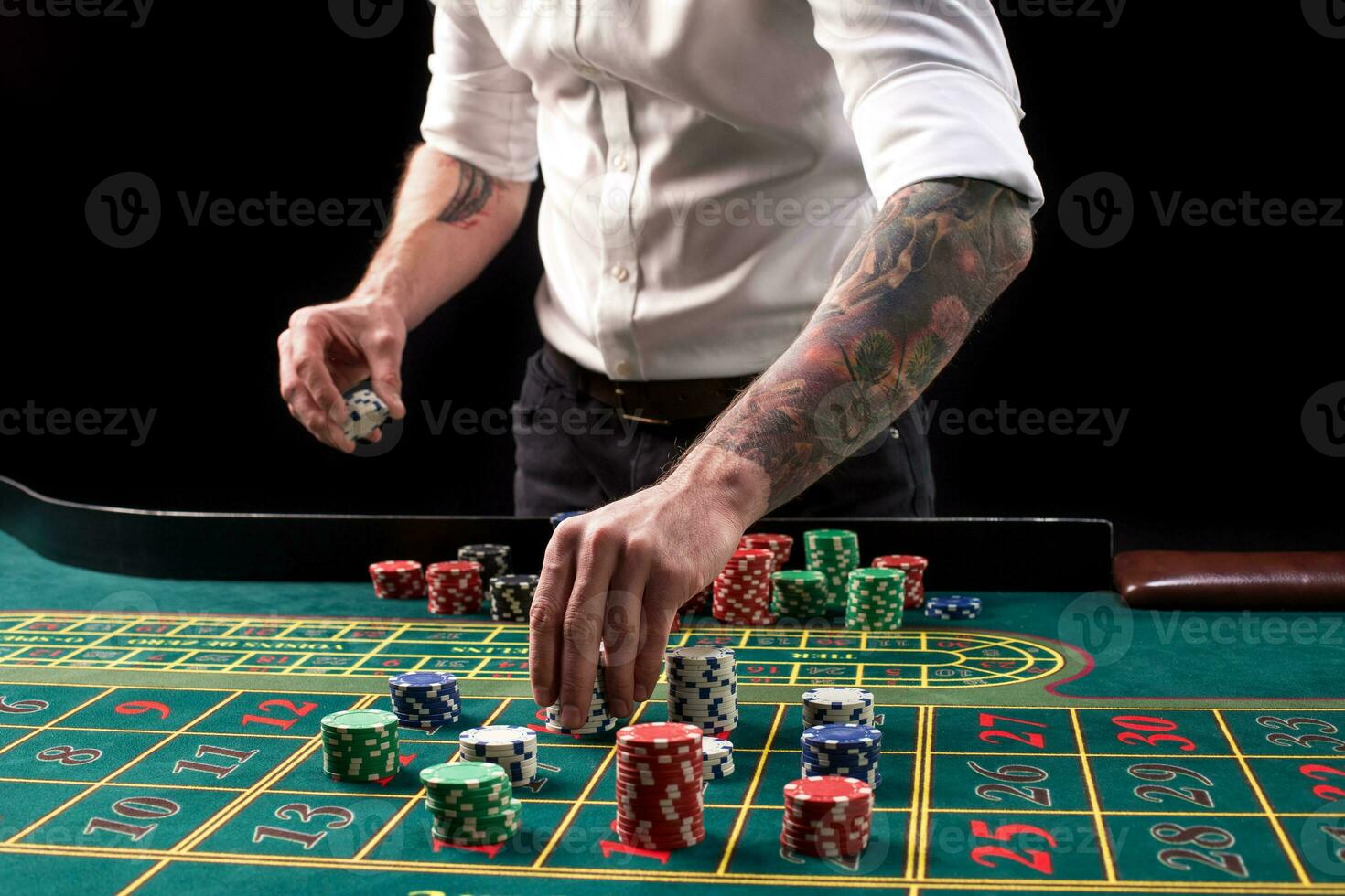 A close-up vibrant image of green casino table with roulette, with the hands of croupier and multicolored chips. photo