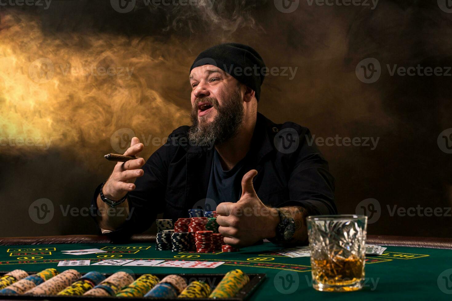 Man is playing poker with a cigar and a whiskey. A man winning all the chips on the table with thick cigarette smoke. photo