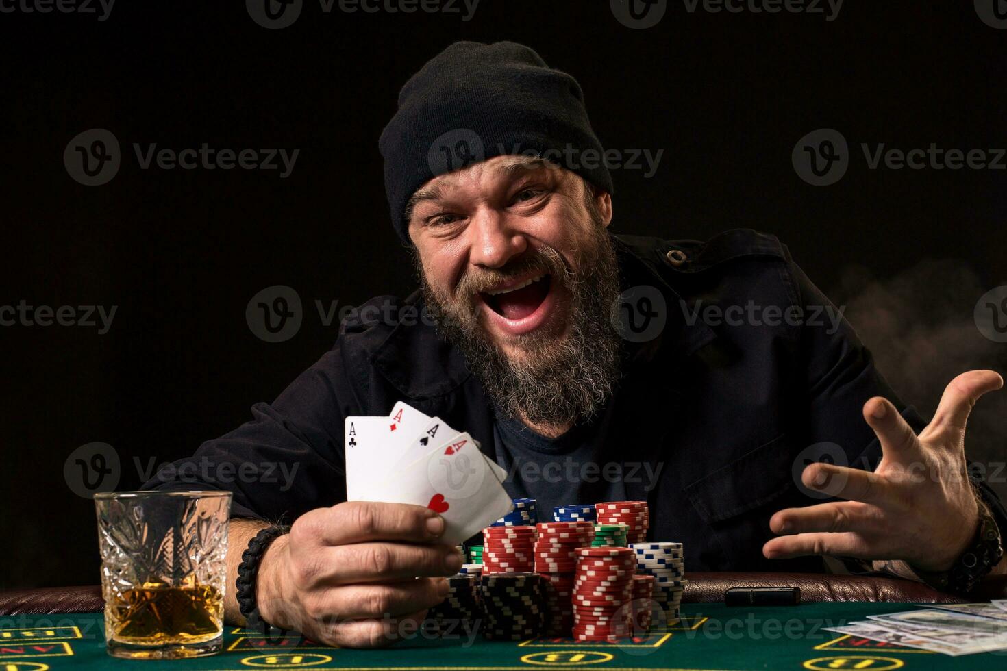 Bearded man drinking whisky while playing poker photo