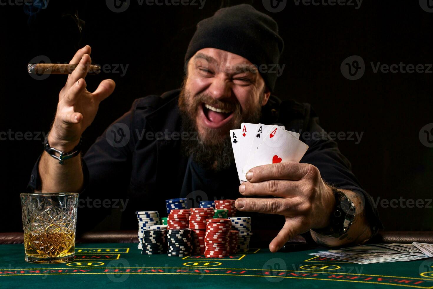 Bearded man drinking whisky and smoking a cigar while playing poker photo