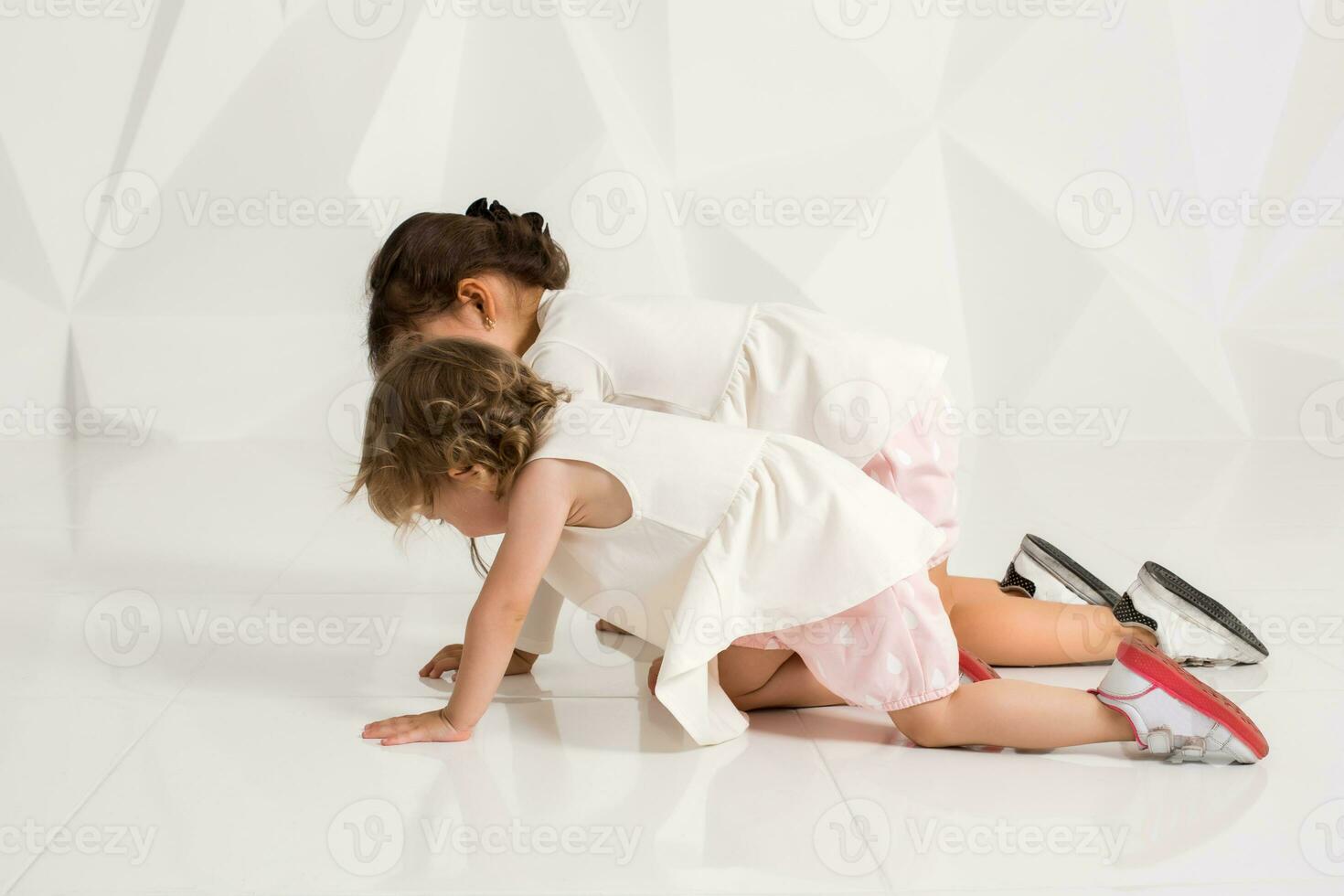 Children sisters play together on white background photo