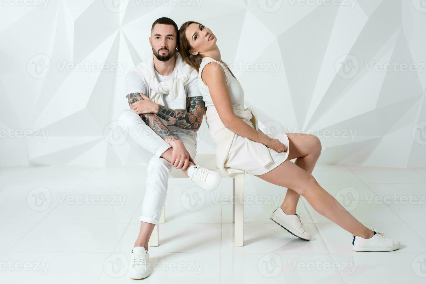 Casual couple near a white wall, man and woman in white clothing. photo