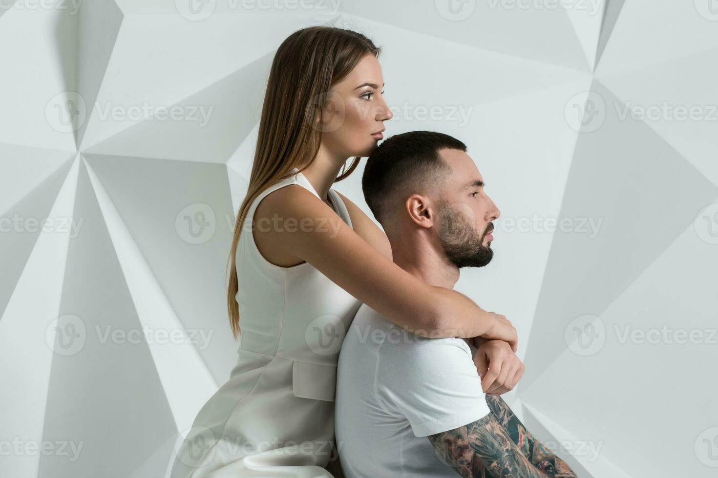 Portrait of a beautiful young couple in love posing at studio over white background. photo