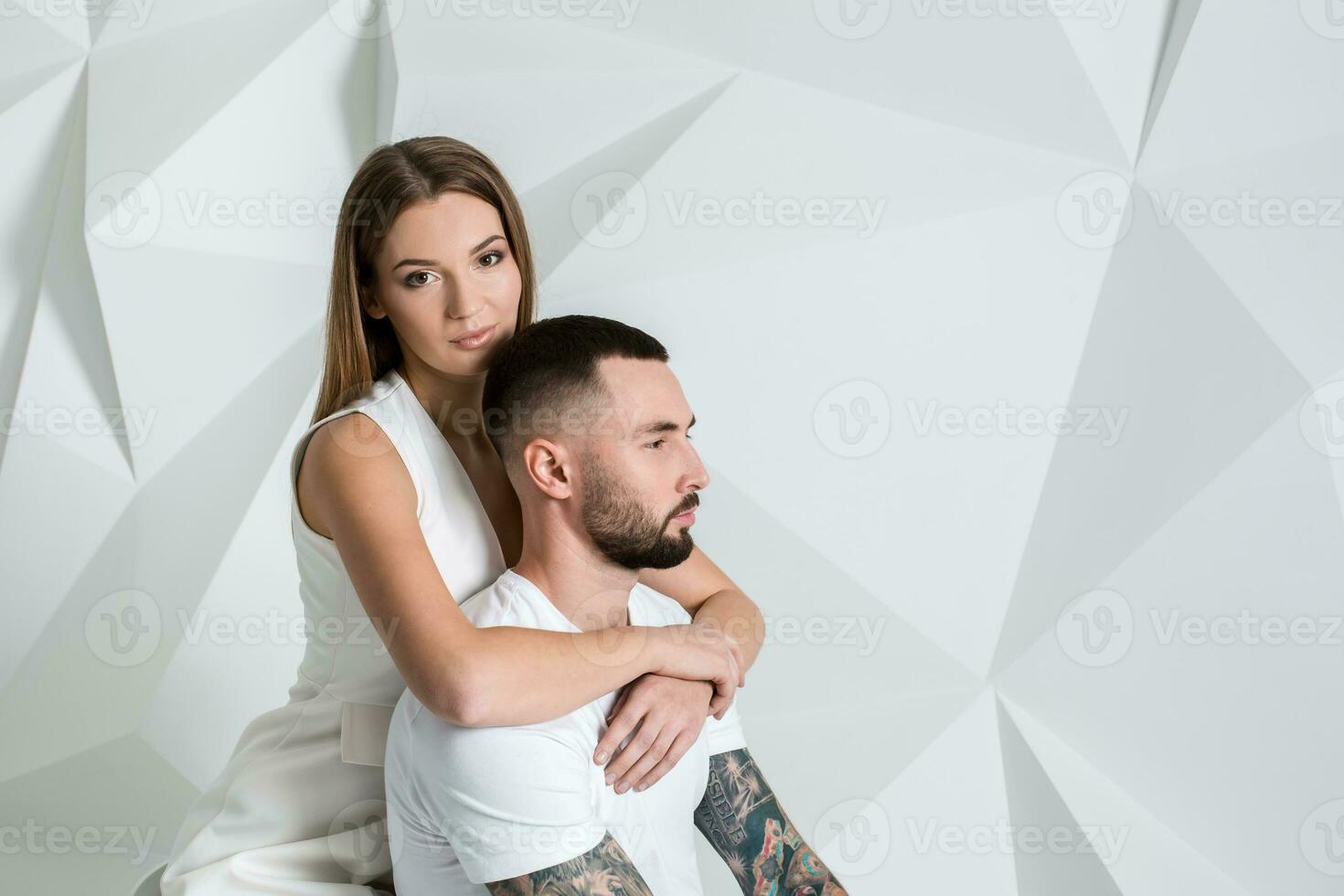 Portrait of a beautiful young couple in love posing at studio over white background. photo