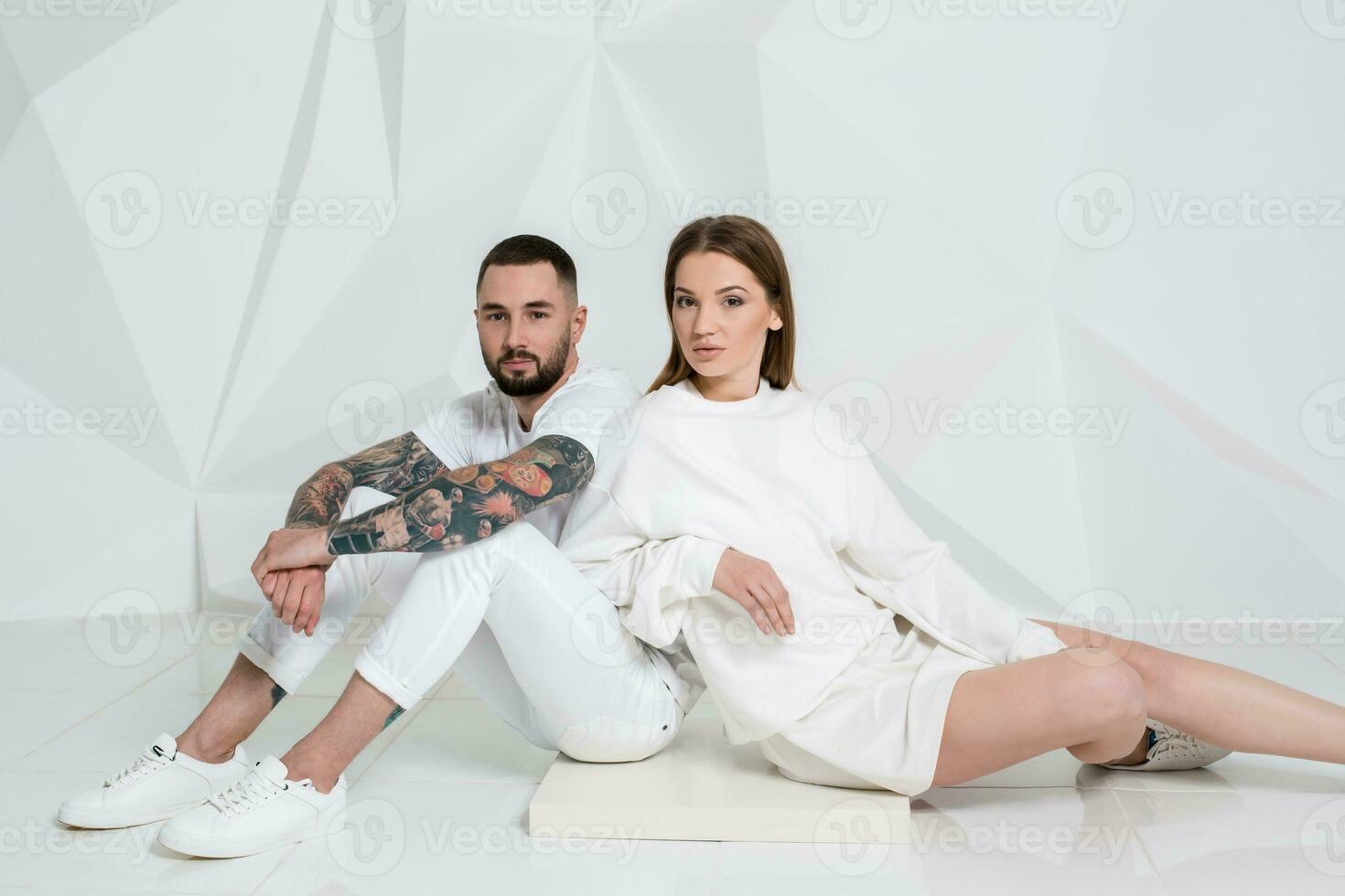 Portrait of a beautiful young couple in love posing at studio over white background. photo