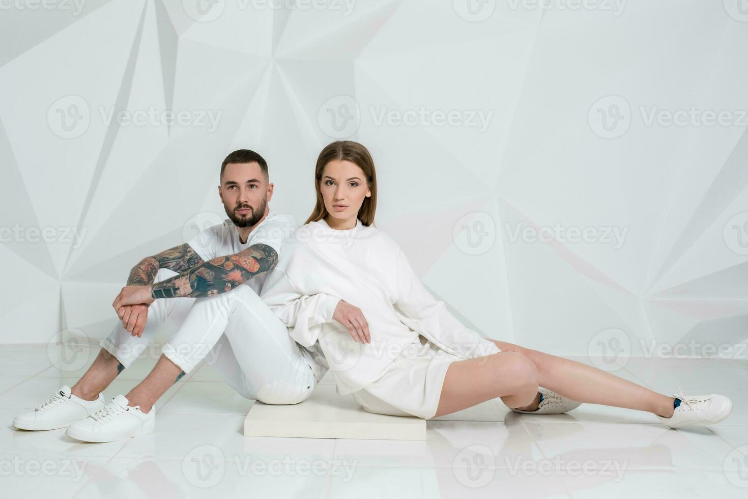 Portrait of a beautiful young couple in love posing at studio over white background. photo
