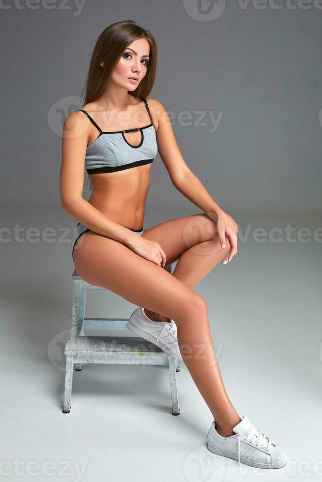 Beautiful girl in sports underwear isolated on gray background photo