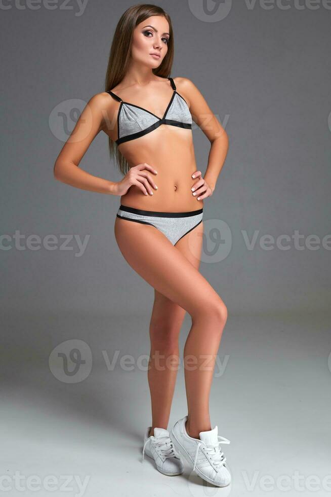 Beautiful girl in sports underwear isolated on gray background photo