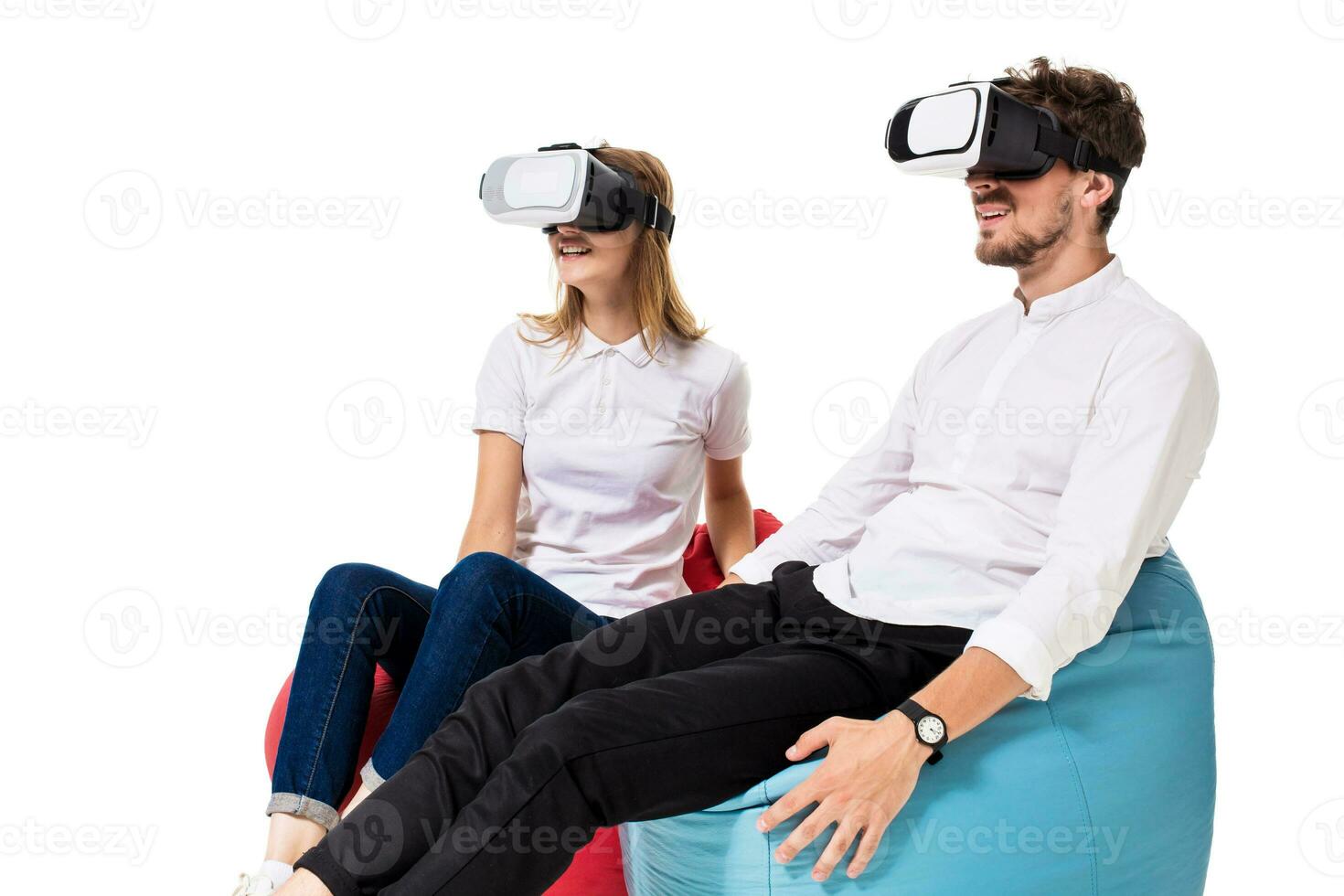 Excited young couple experiencing virtual reality seated on beanbags isolated on white background photo