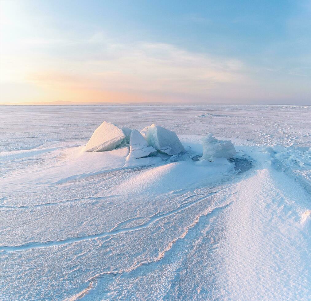 invierno paisaje. ventisqueros en el hielo superficie durante puesta de sol. foto