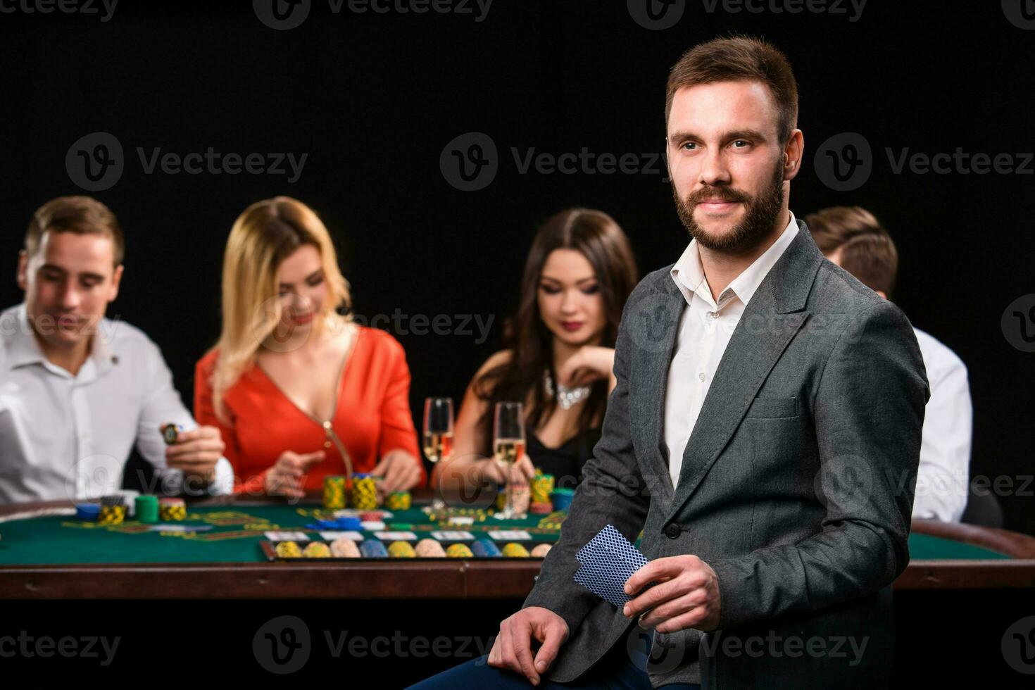 Poker players in casino with cards and chips on black background photo