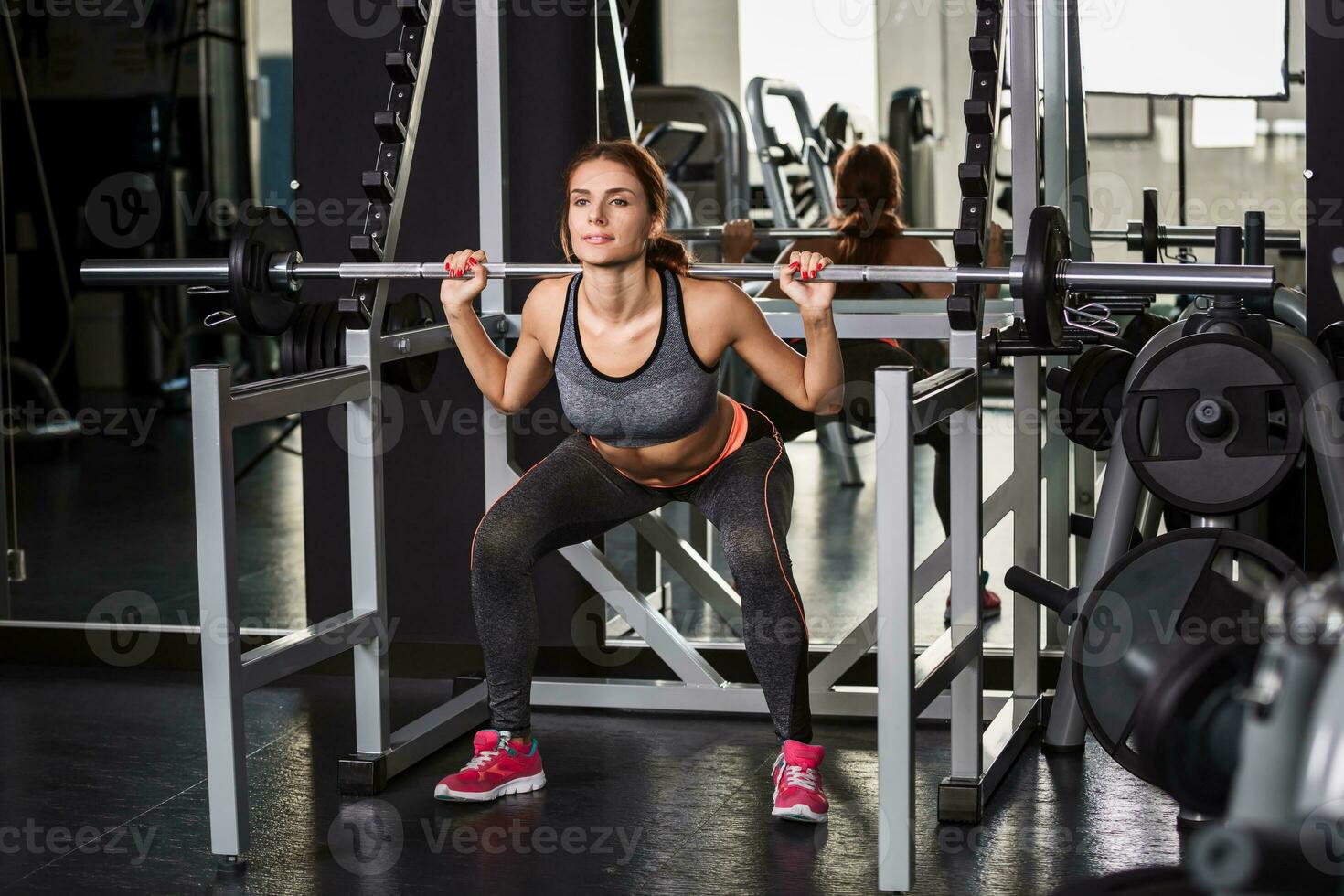 muscular joven mujer haciendo ejercicios en el simulador en el gimnasio foto