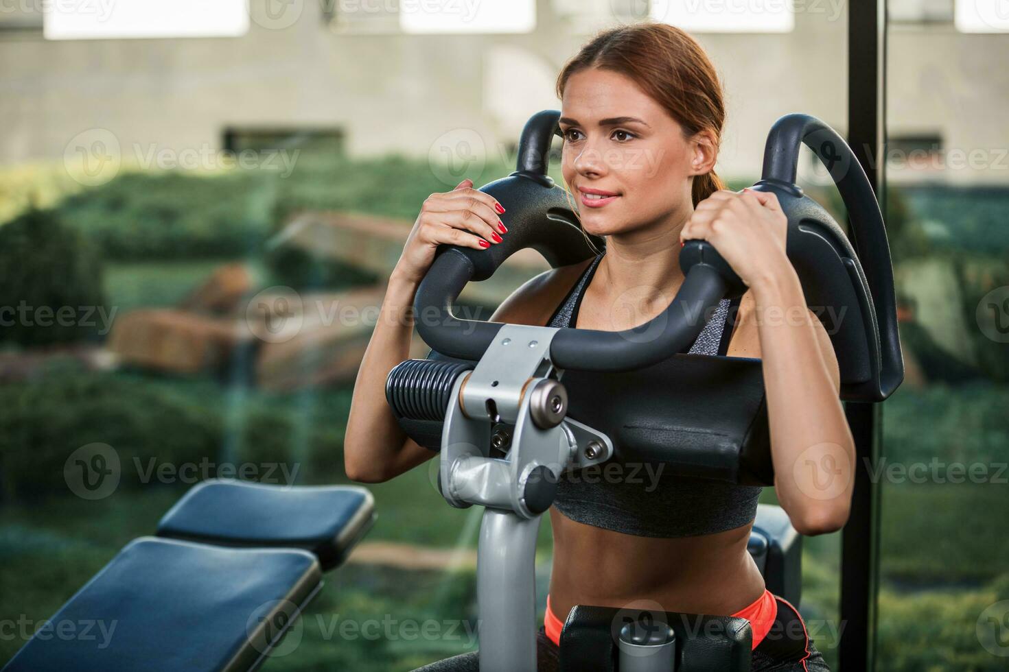 Muscular young woman doing exercises on the simulator in the gym photo