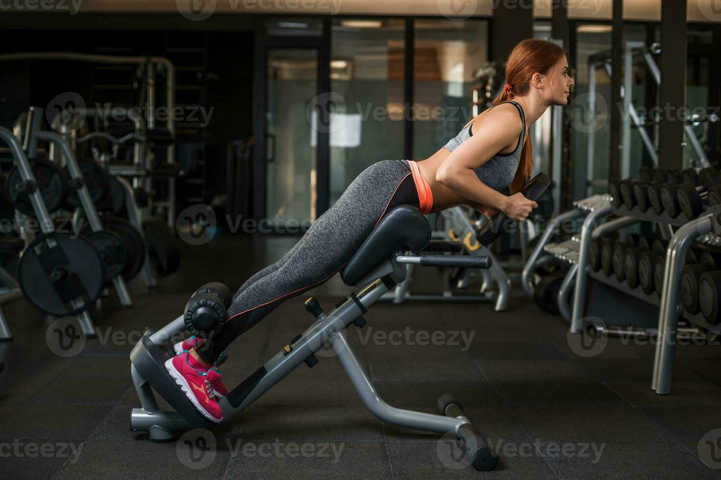 Muscular young woman doing exercises on the simulator in the gym photo