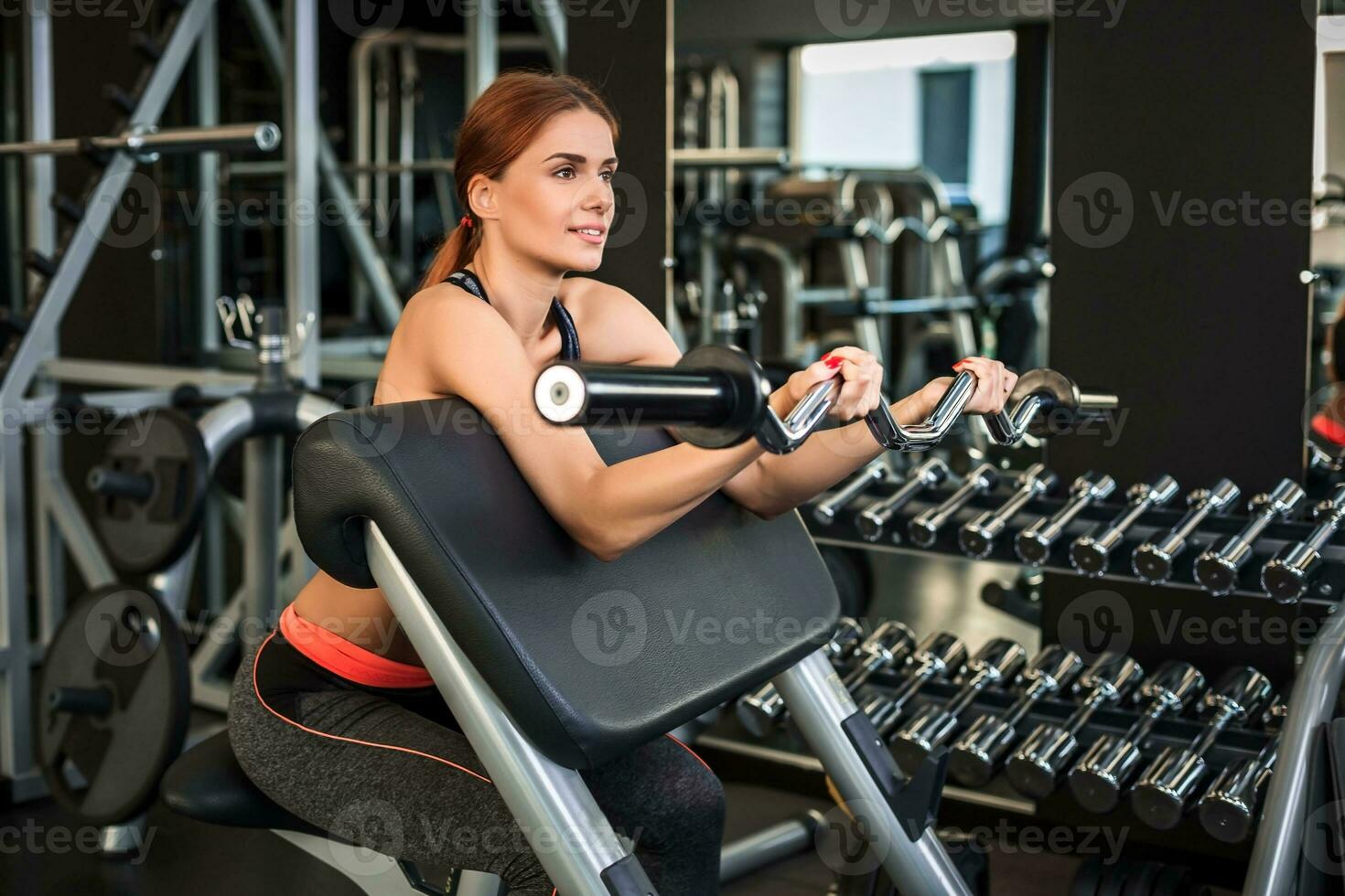 Muscular young woman doing exercises on the simulator in the gym photo