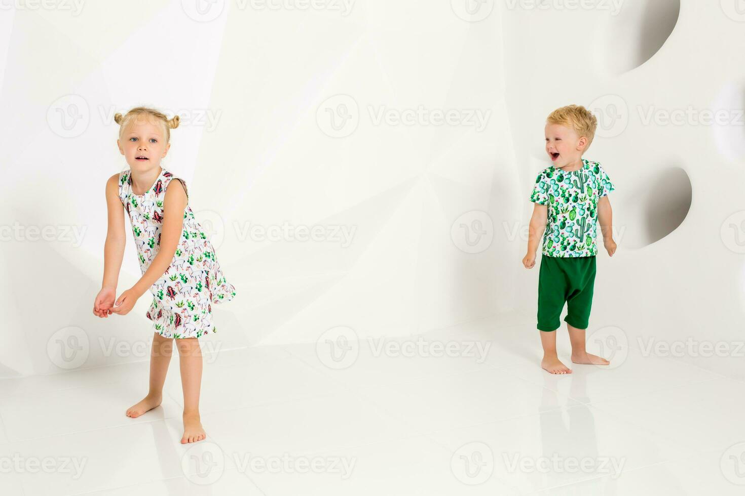 hermano y hermana jugando y sonriente en un blanco estudio foto