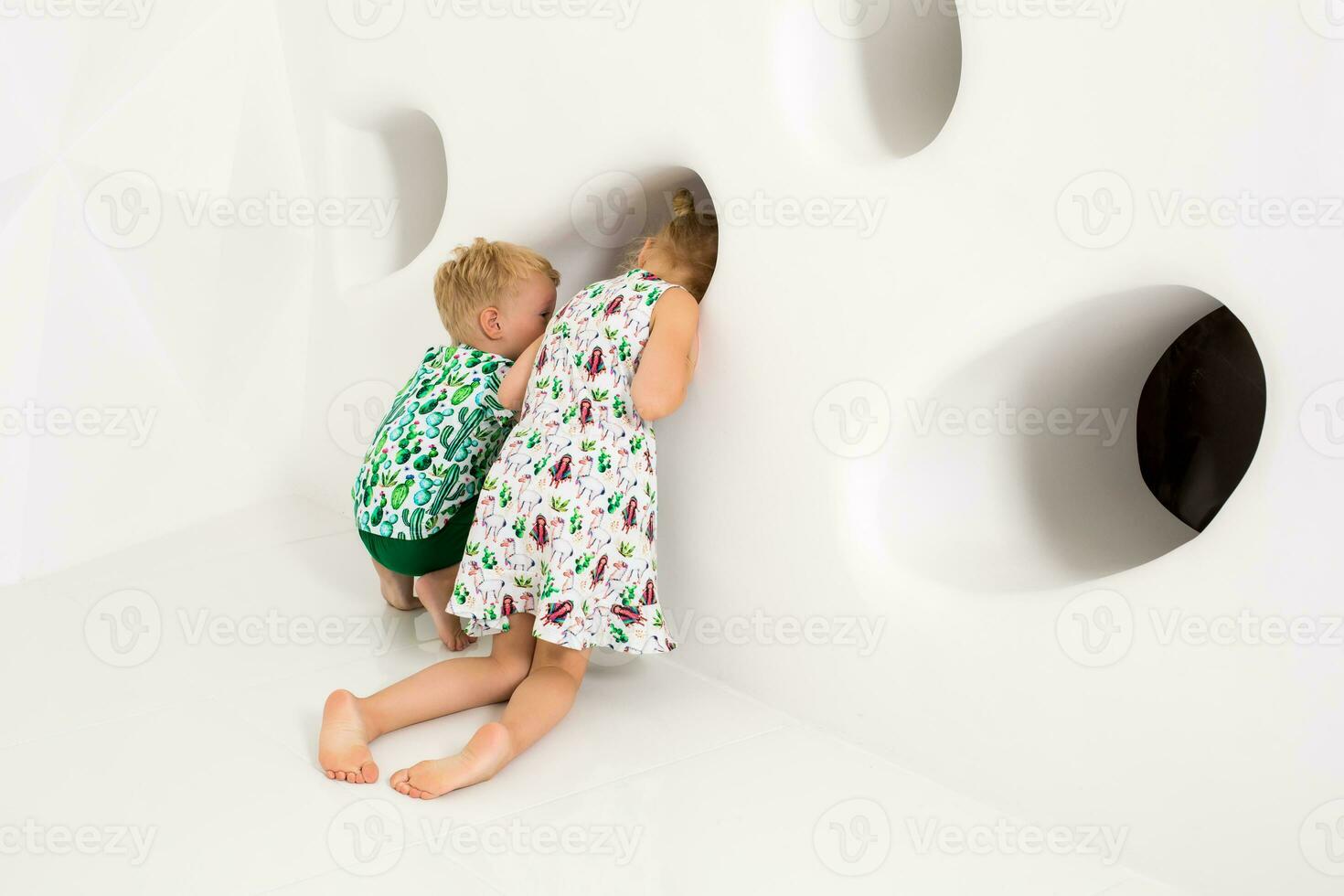 Brother and sister playing and smiling in a white studio photo