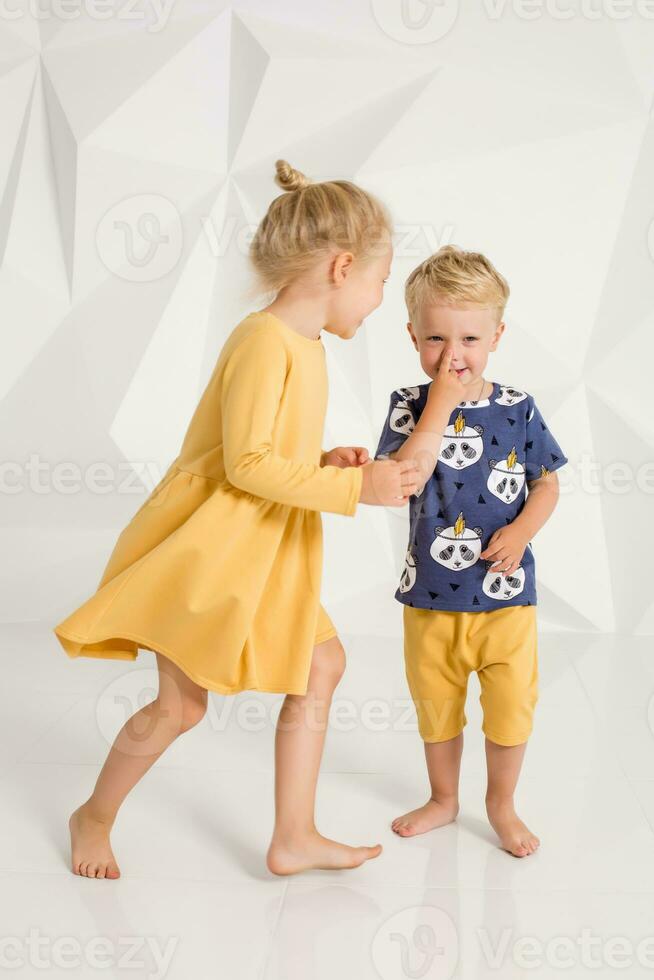 Brother and sister playing and smiling in a white studio photo