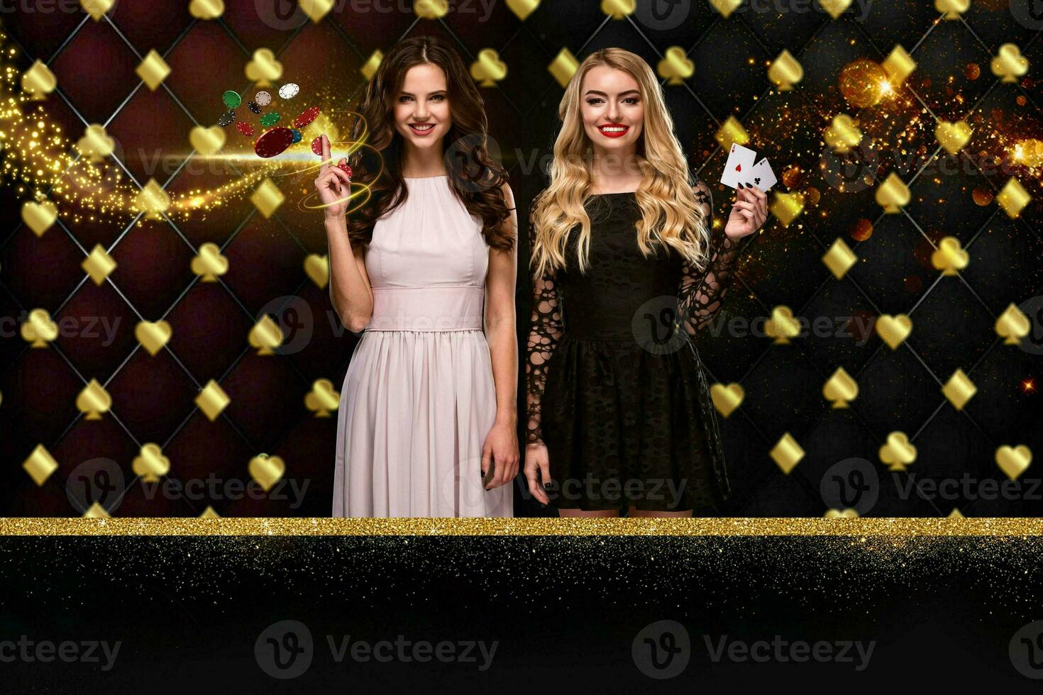 Two girls are showing two aces and chips, smiling, posing against colorful sparkling background with golden card suits. Gambling, poker, casino. photo