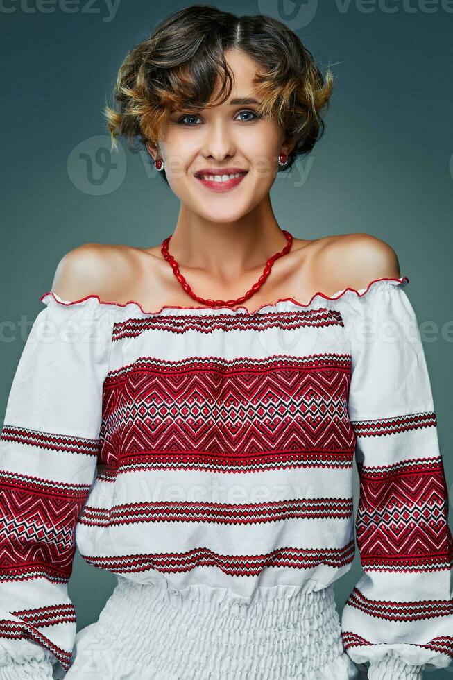 Portrait charming young lady with short wavy hair in embroidery. photo