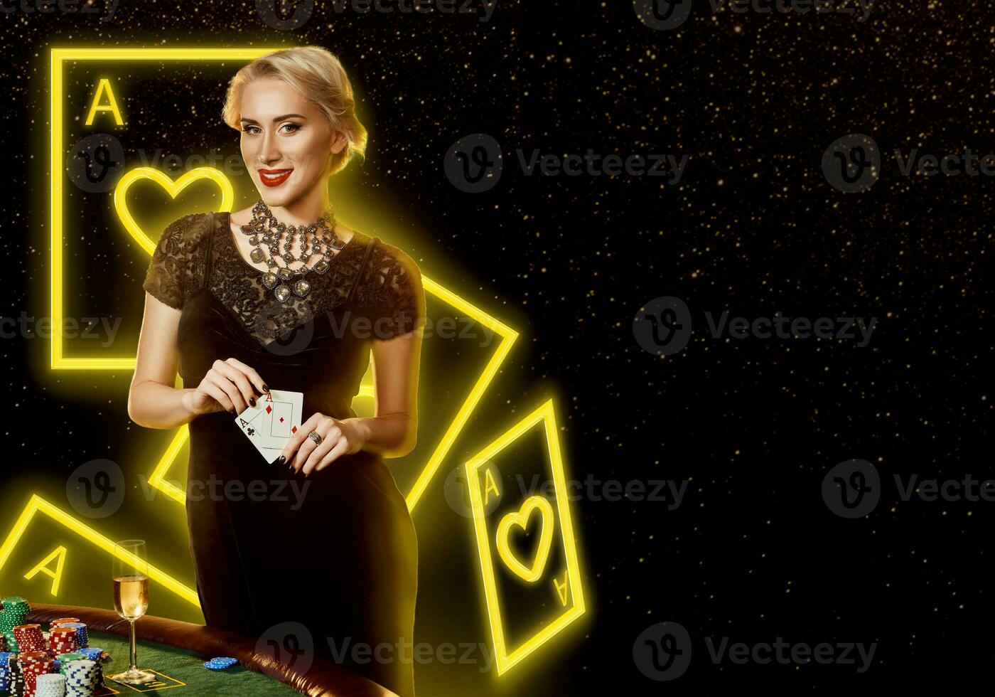 Lady in black dress showing aces, smiling, posing at table with chips and champagne on it. Black background with neon playing cards. Poker, casino photo