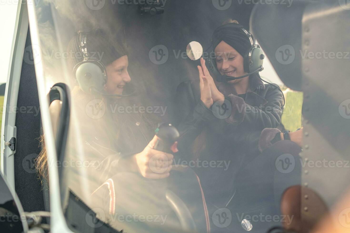 Smiling teenage girls in pilot headsets giving high five in helicopter photo