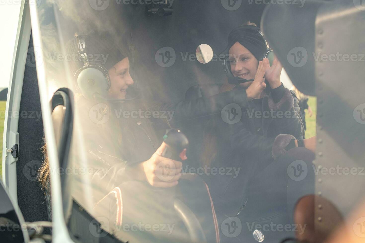Two friendly tween girls giving high five on pilot seats in helicopter photo