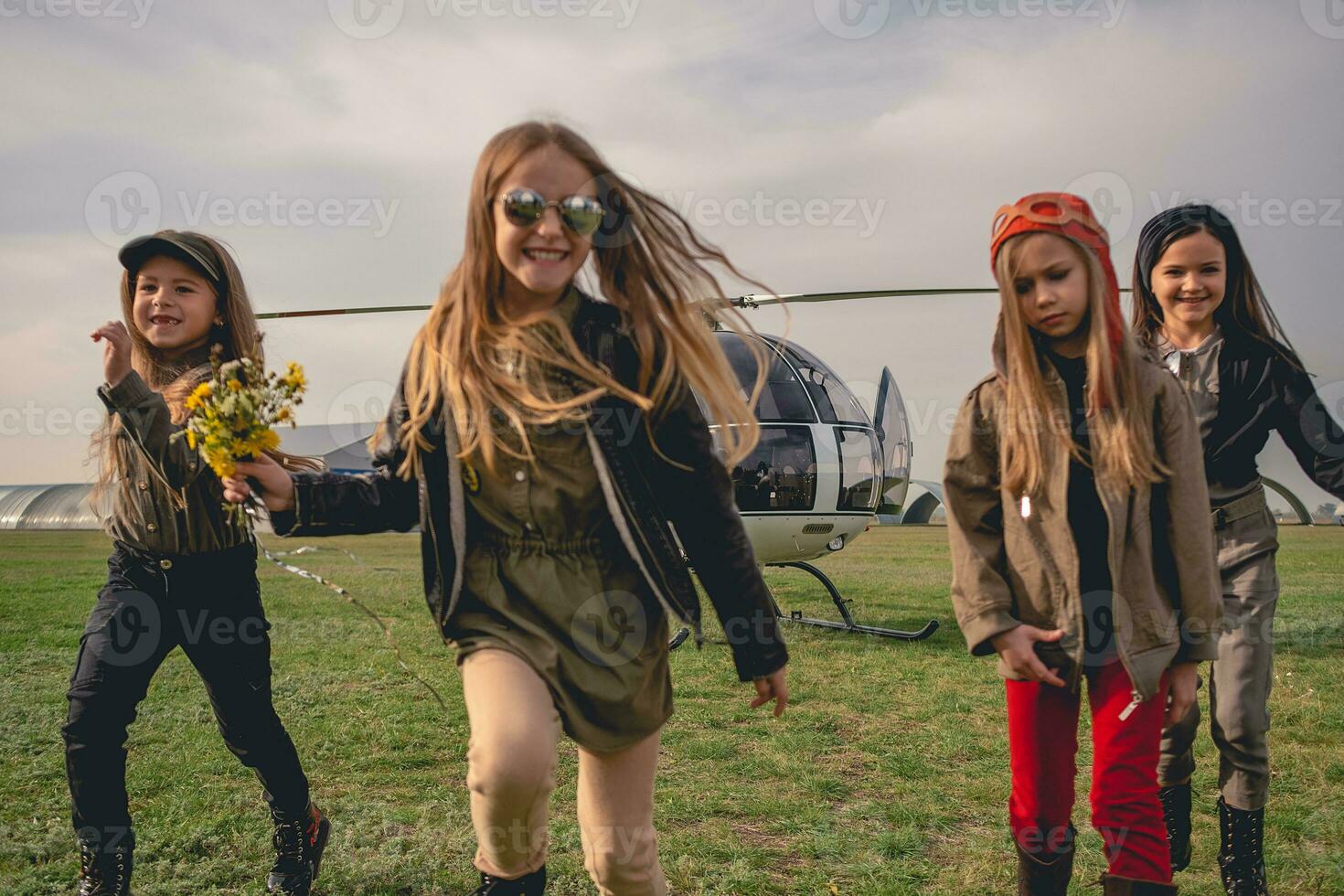 Cheerful tween girls running on airfield on background of helicopter photo