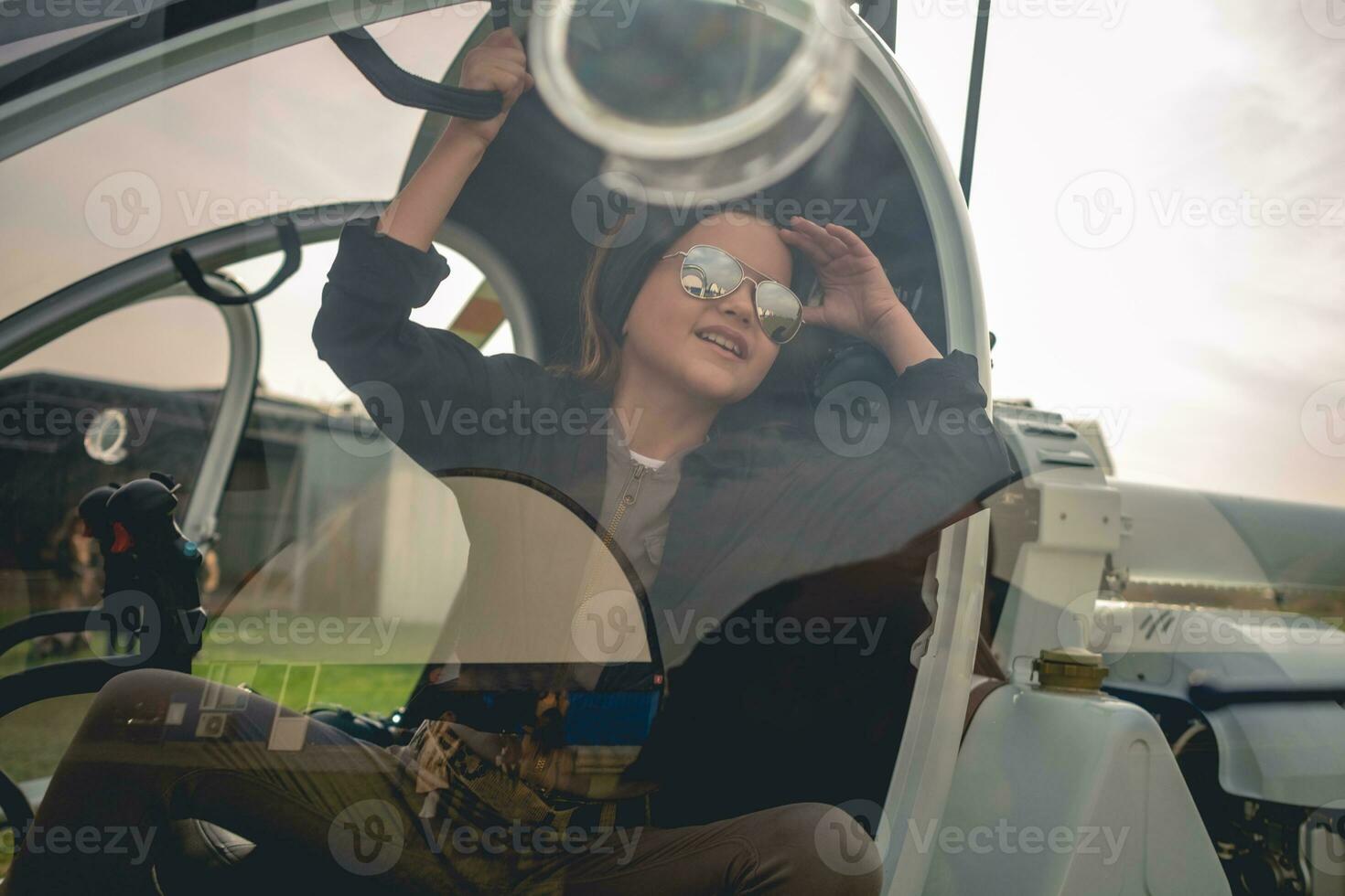 View through glass of helicopter cockpit of cheerful tween girl looking at sky photo