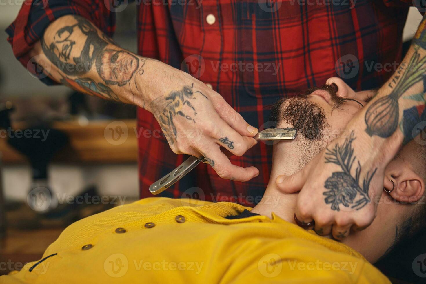 Client during beard shaving in barber shop photo