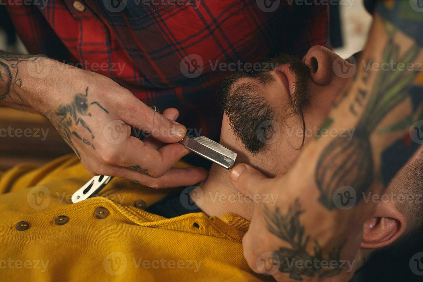 Client during beard shaving in barber shop photo