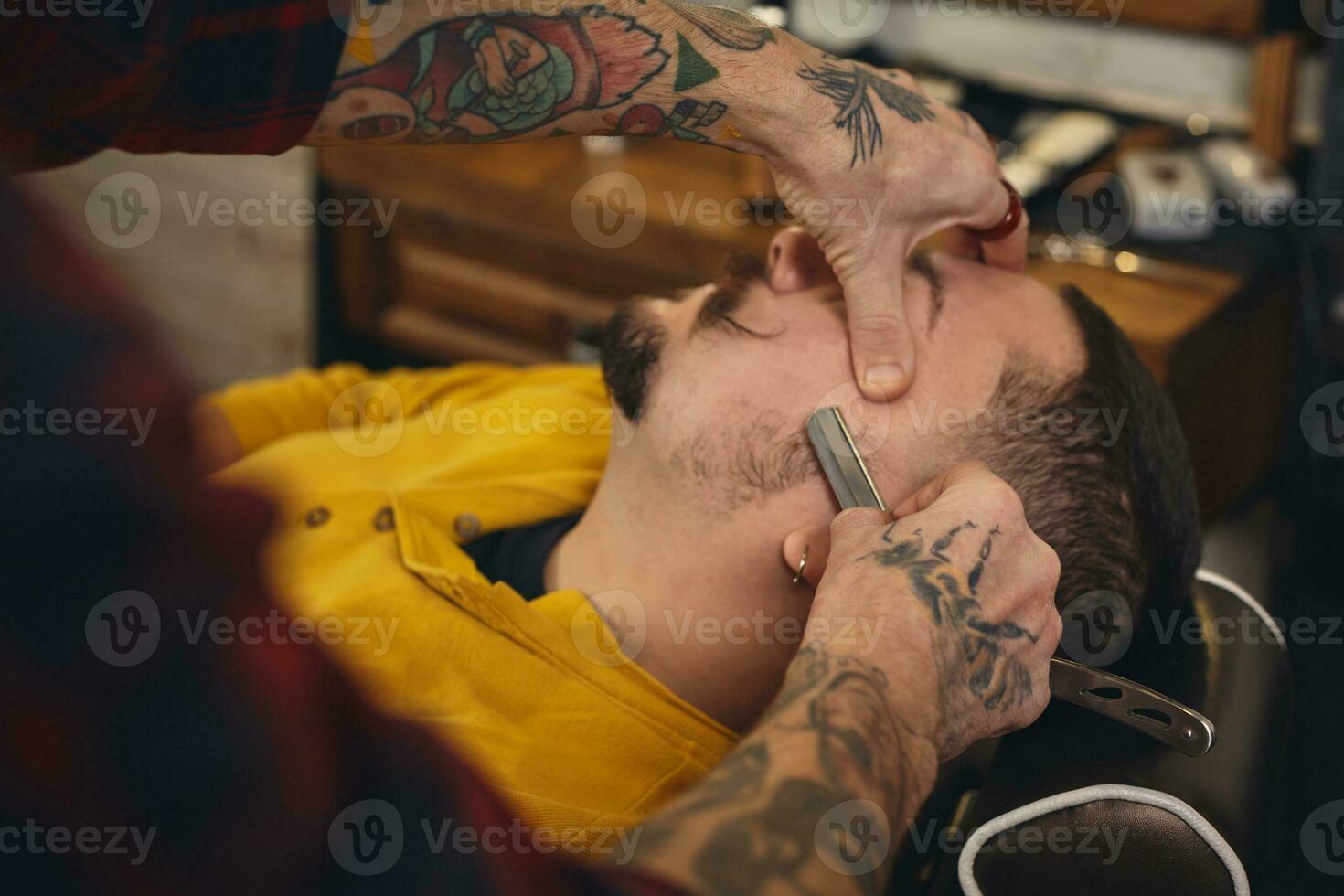 Client during beard shaving in barber shop photo