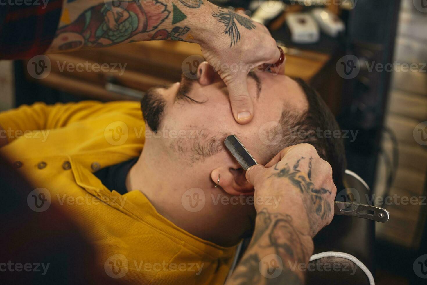 Client during beard shaving in barber shop photo