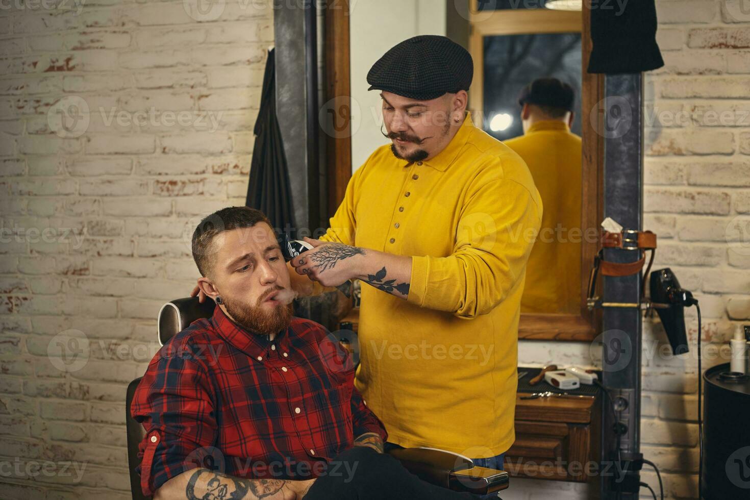 Barber making haircut of attractive bearded man in barbershop photo
