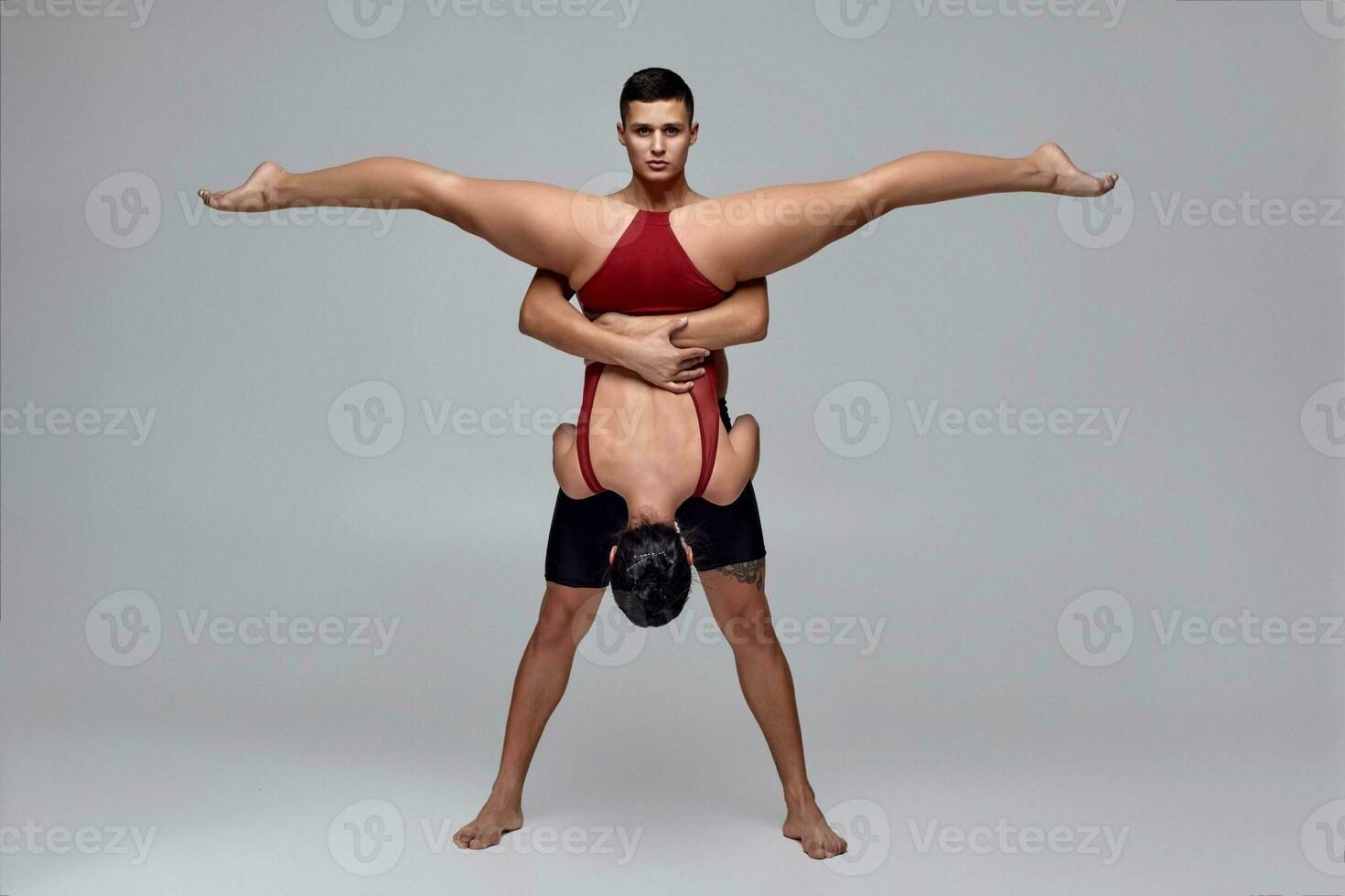The couple of an athletic modern ballet dancers are posing against a gray studio background. photo