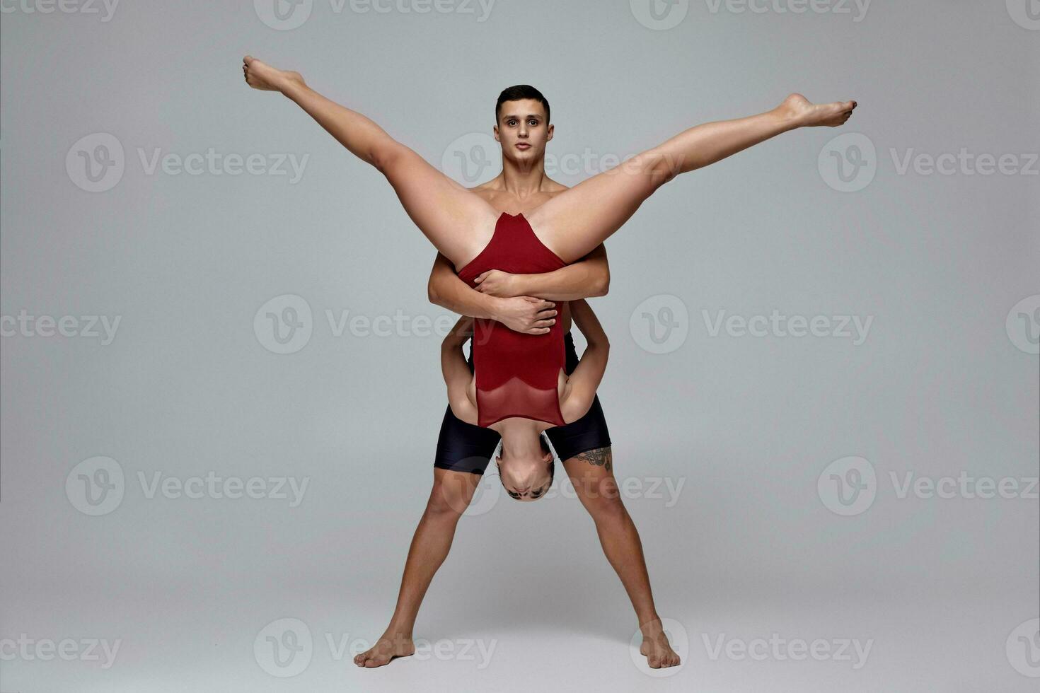 The couple of an athletic modern ballet dancers are posing against a gray studio background. photo