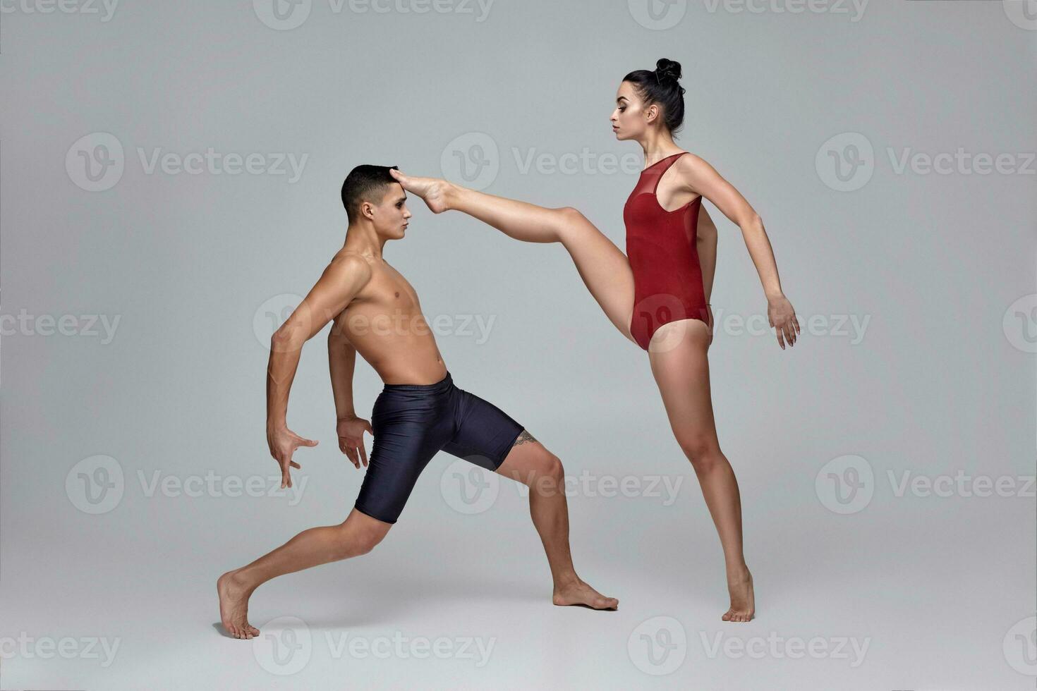 The couple of an athletic modern ballet dancers are posing against a gray studio background. photo