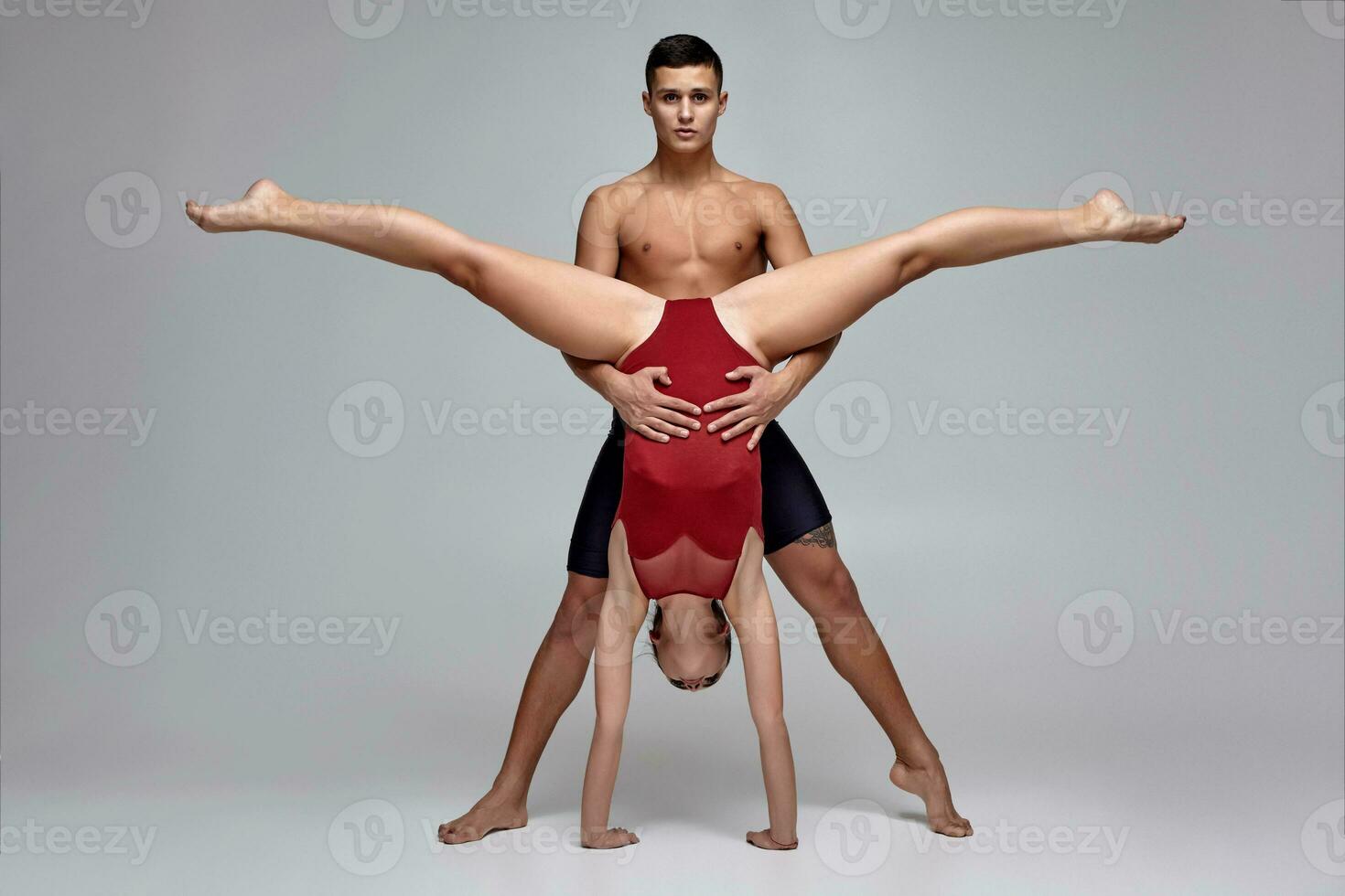 The couple of an athletic modern ballet dancers are posing against a gray studio background. photo