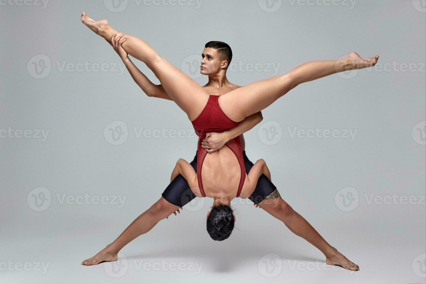 The couple of an athletic modern ballet dancers are posing against a gray studio background. photo