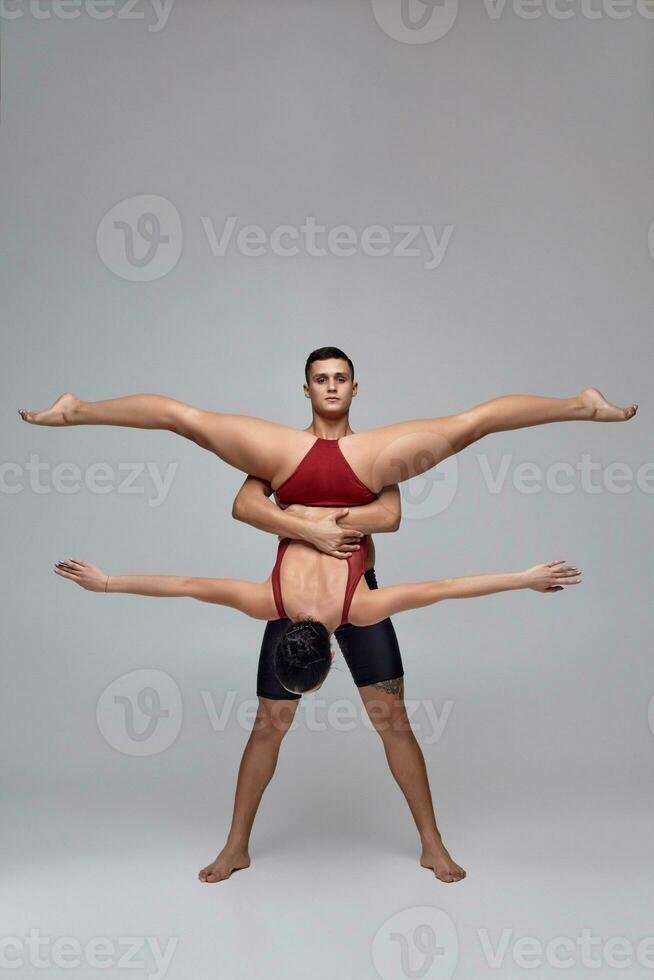 The couple of an athletic modern ballet dancers are posing against a gray studio background. photo