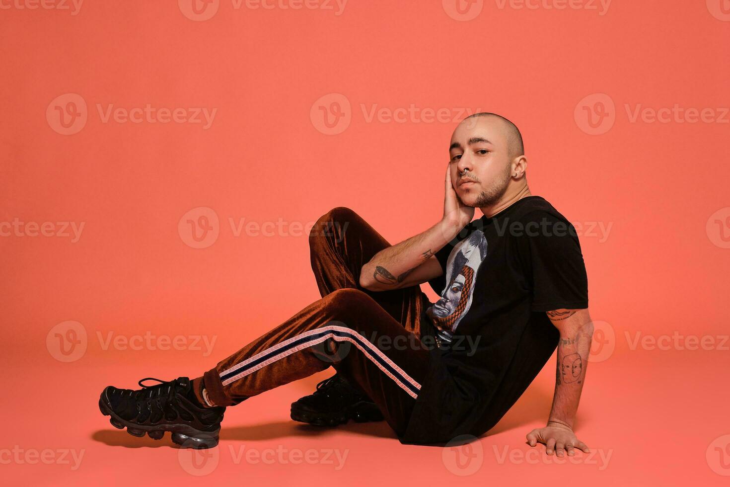 estudio Disparo de un joven tatuado calvo hombre posando en contra un rosado antecedentes. 90s estilo. foto