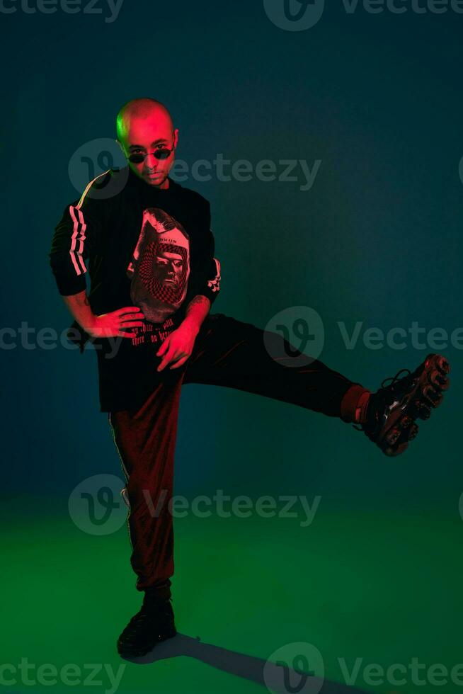 Studio shot of a young tattoed bald man posing against a colorful background. 90s style. photo