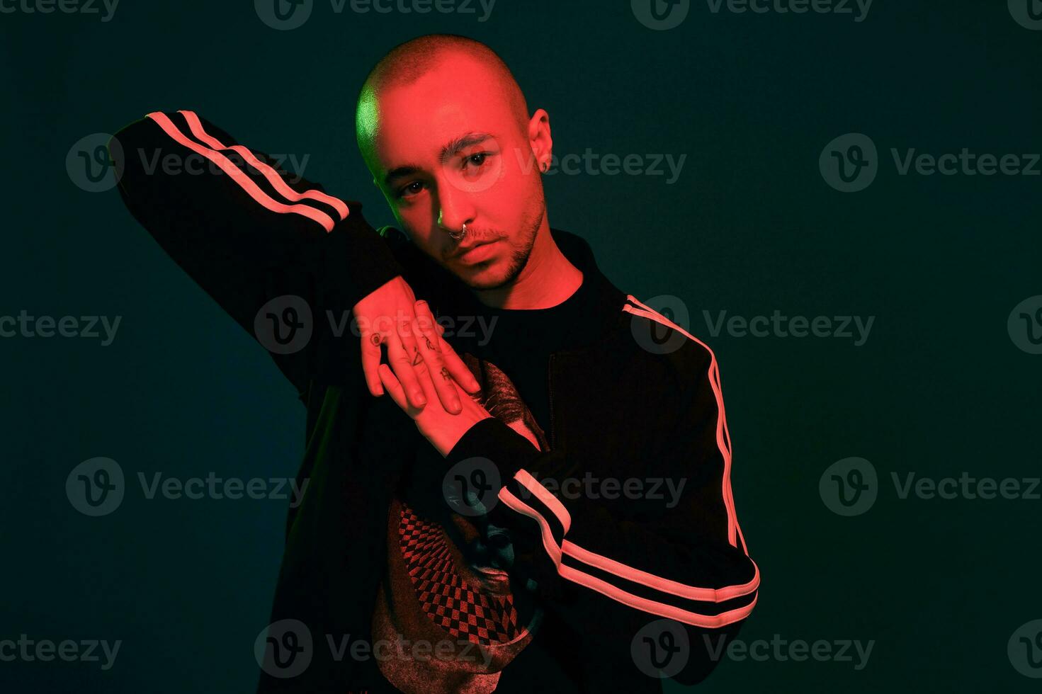 Studio shot of a young tattoed bald man posing against a colorful background. 90s style. photo