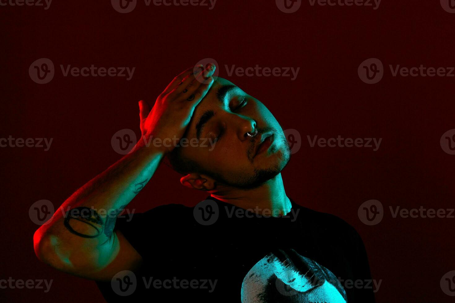 Studio shot of a young tattoed bald man posing against a red background. 90s style. photo