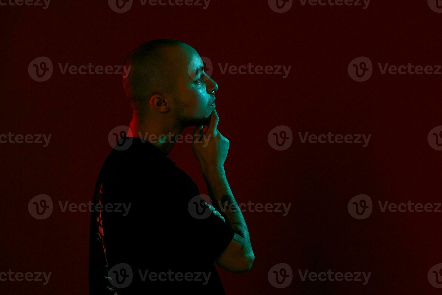 estudio Disparo de un joven tatuado calvo hombre posando en contra un rojo antecedentes. 90s estilo. foto