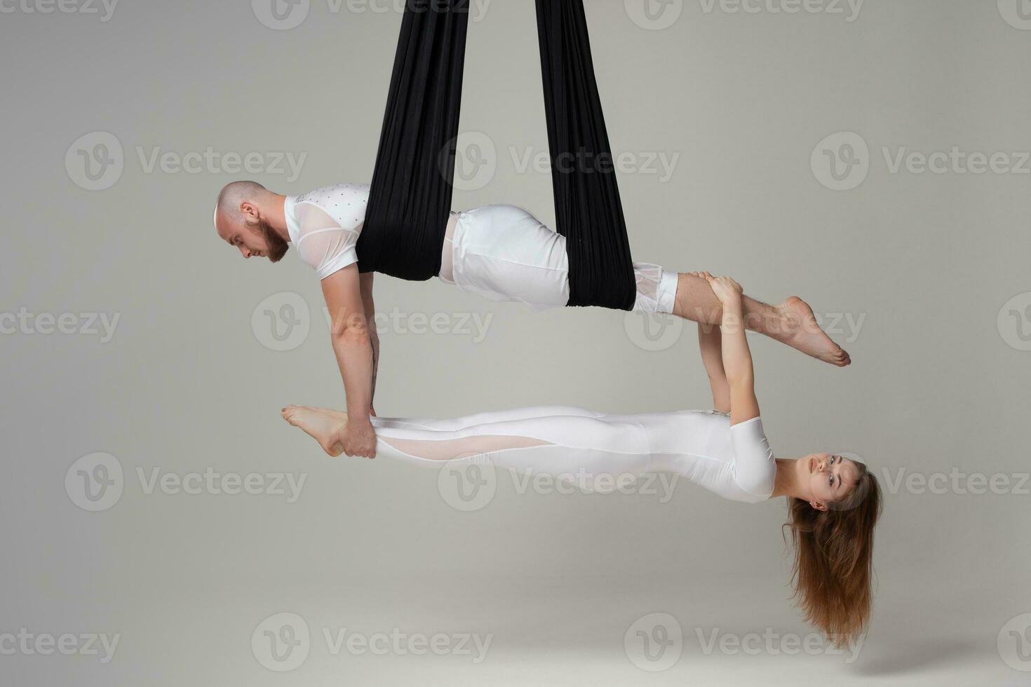 hermosa niña y un atlético hombre en un blanco deporte trajes son ejecutando un acrobático elementos en un estudio. foto