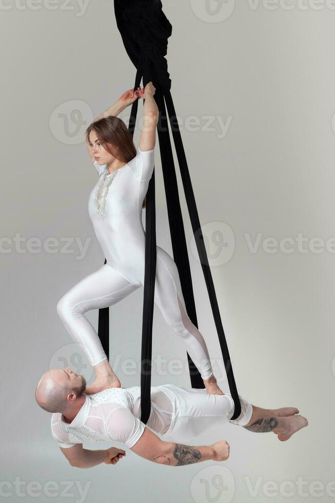 hermosa niña y un atlético hombre en un blanco deporte trajes son ejecutando un acrobático elementos en un estudio. foto